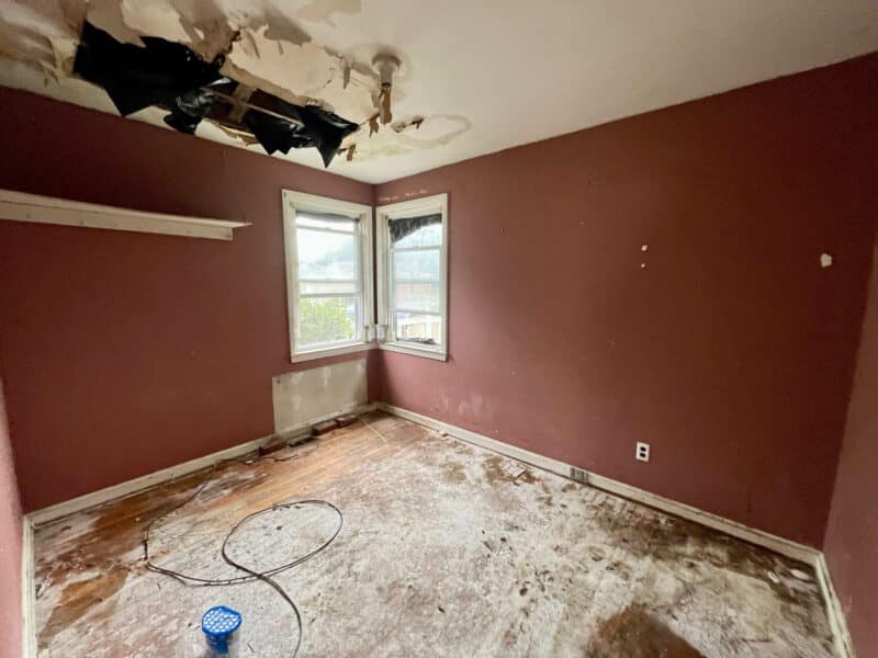 Bedroom at 4902 Gilray Drive with damaged ceiling, exposed subflooring, and red-painted walls.