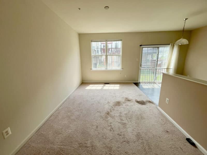 Dining area with large windows and carpet flooring in Baltimore townhouse.