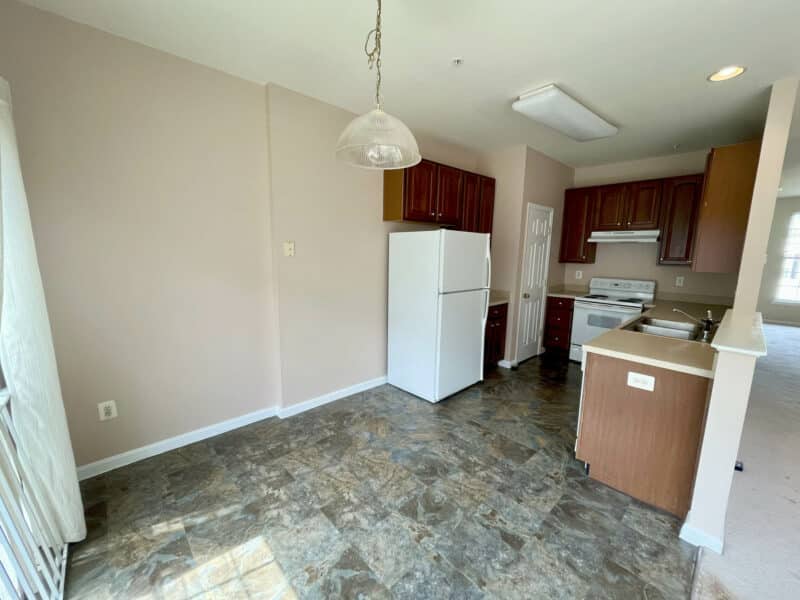 Eat-in kitchen with pendant light, tile flooring, and wood cabinetry.