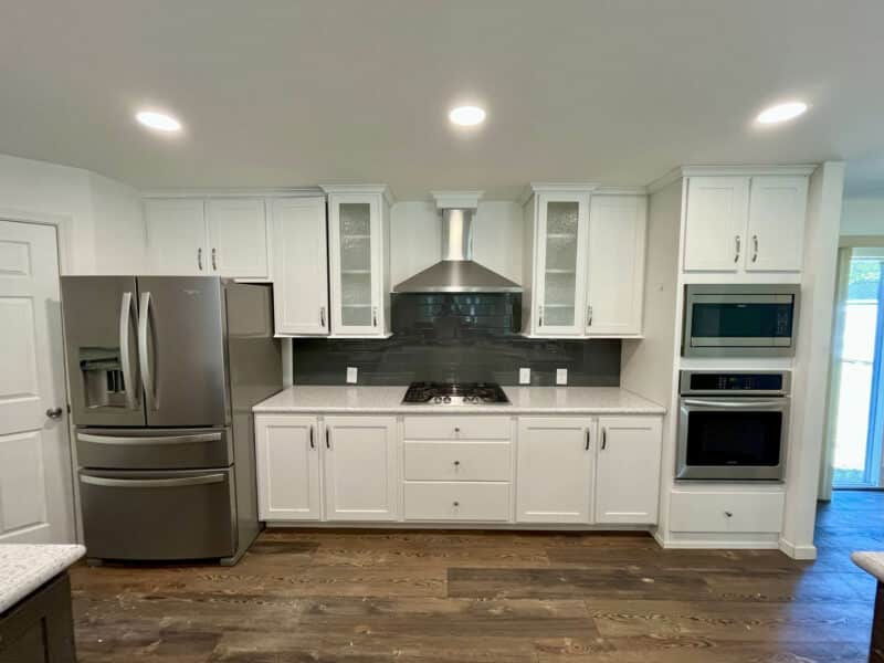 Kitchen wall with stainless steel refrigerator, gas cooktop, and wall oven.