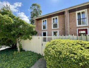 Front view of brick townhouse condo with fenced entry