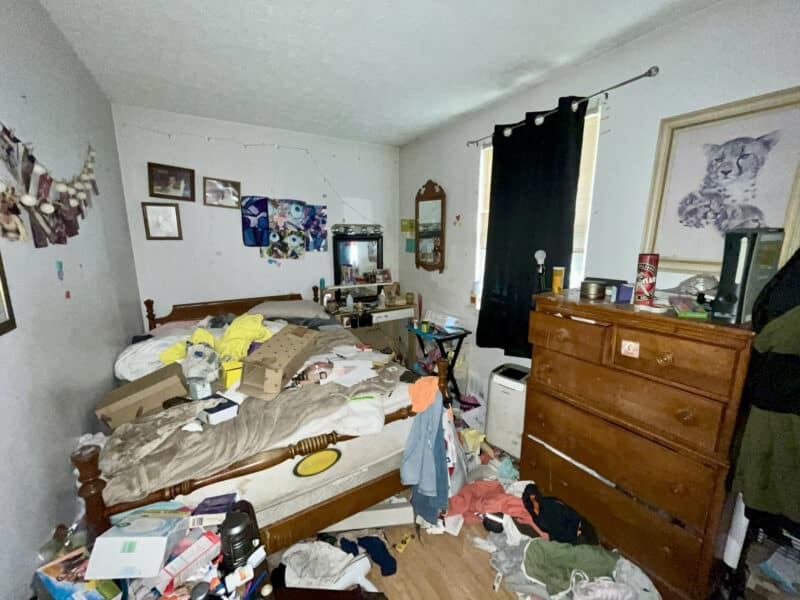 Cluttered bedroom at 2009 Halethorpe Avenue in Halethorpe Terrace, Baltimore County, with hardwood floors, dresser, bed, and wall décor, showing renovation potential.