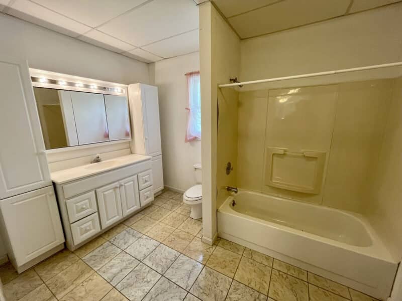 Full bathroom with large vanity, tub/shower combo, and tiled floor.