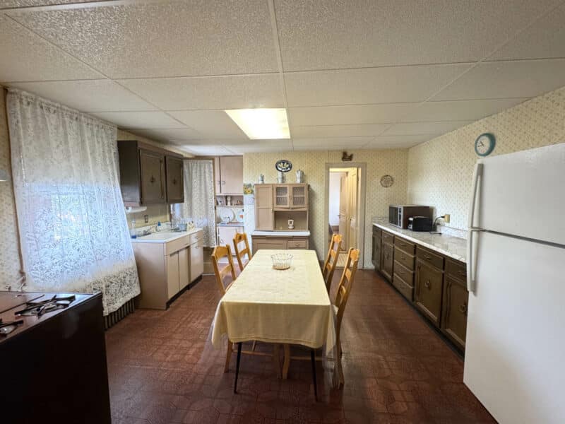 Large kitchen with long dining table, wood cabinetry, and vintage appliances.