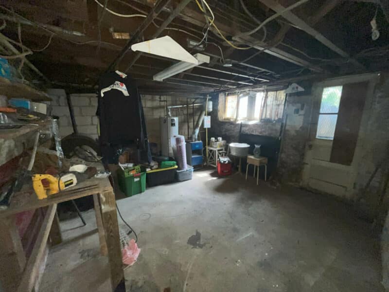 Unfinished basement area with exposed block walls, utilities, and storage.