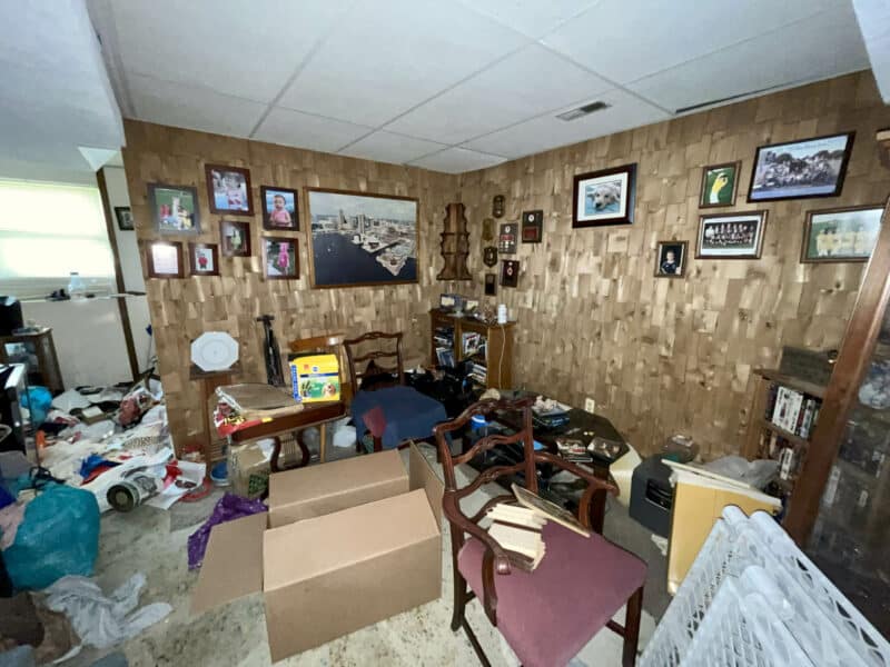 Living area at 2009 Halethorpe Avenue in Halethorpe Terrace, Baltimore County, with wood-paneled walls, carpeting, and space for seating, requiring renovation.