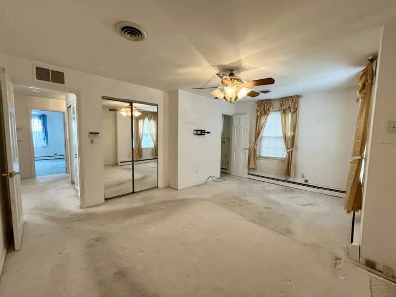 Primary bedroom with mirrored closet and ceiling fan at 7245 Meadow Lane in Dundalk Farms, MD.