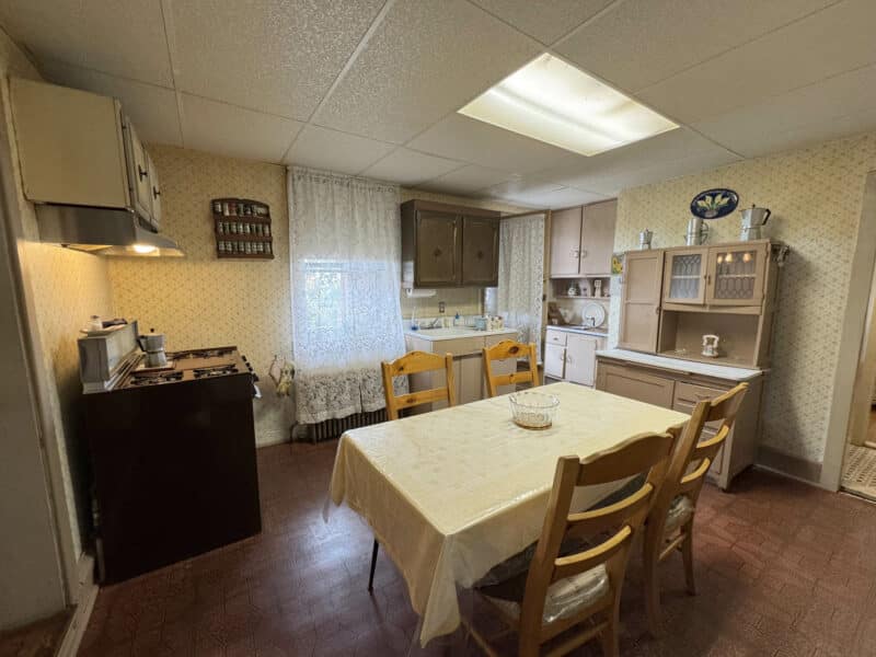 Alternate view of kitchen showing stove, table, and cabinets.