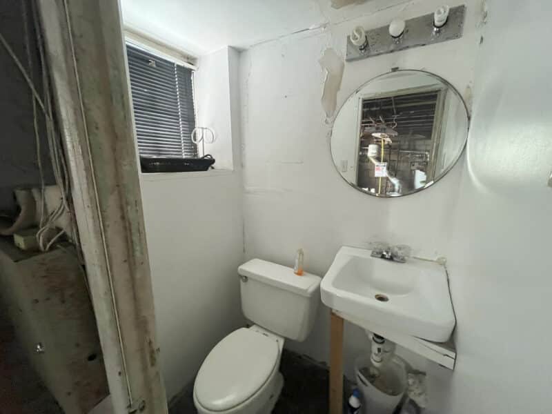 Basement half bathroom with sink, toilet, and small window.