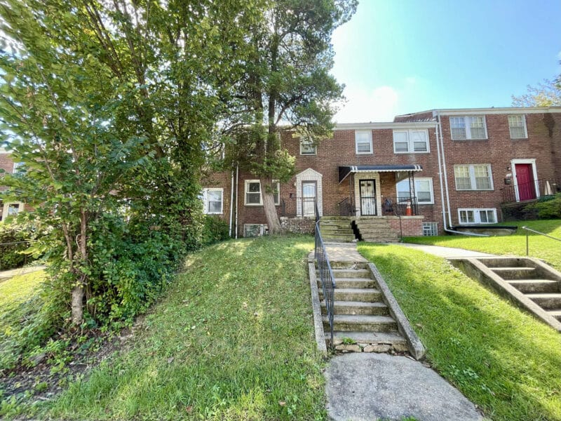 Front exterior of brick two-story Hillen townhome at 1625 Argonne Drive with steps, railings, and small front yard.
