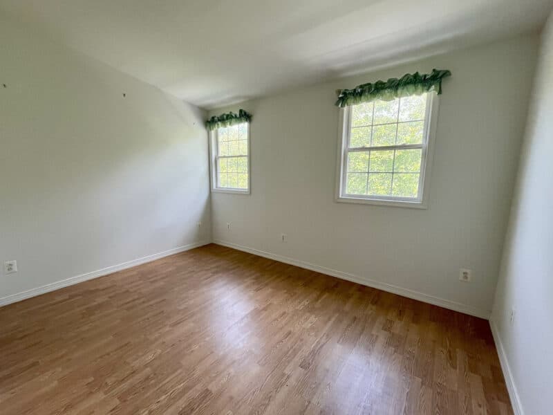 Bedroom with LVP floors and corner windows.