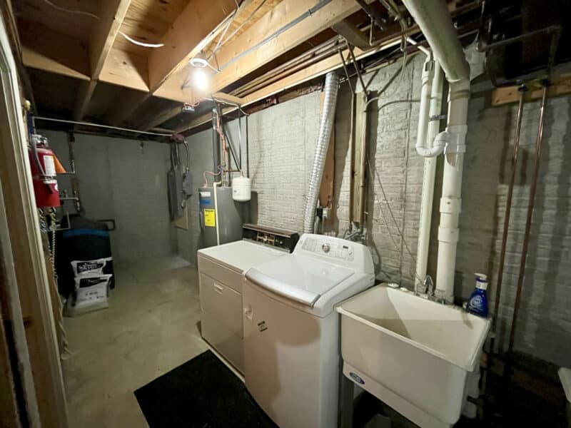 Laundry area in basement with washer, utility sink, and exposed mechanical systems at 334 Royer Road, Westminster, MD.