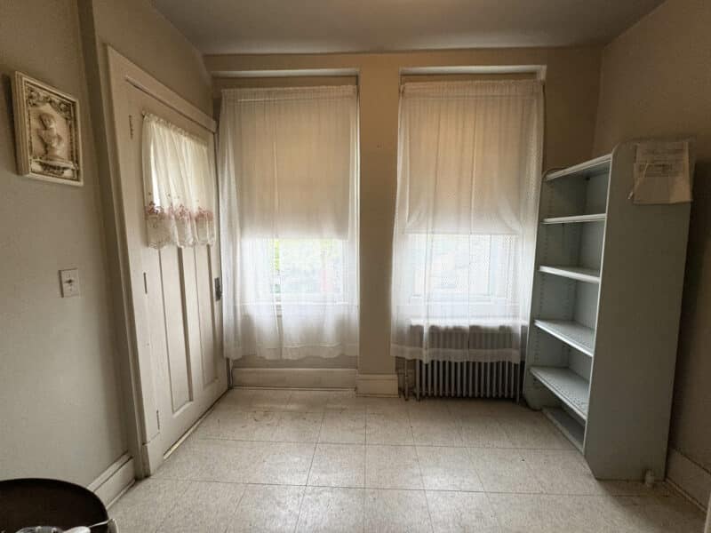 Small room tiled floor, radiator, and shelving.