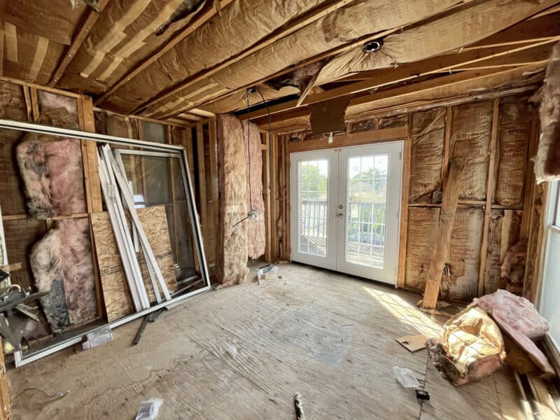 Framed room with exposed insulation, ceiling joists, and sliding glass doors to deck.