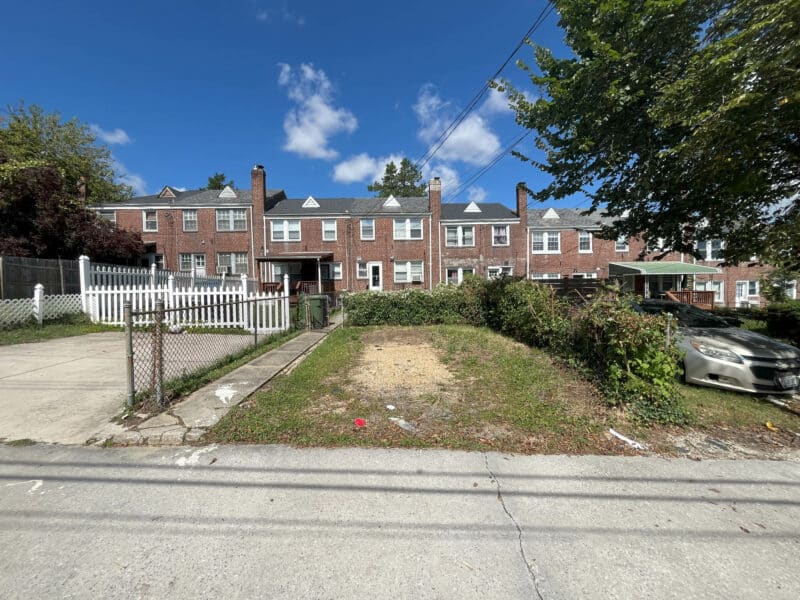 Rear yard with grass, alley access, and parking pad.