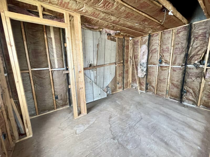 Interior room with fiberglass insulation installed between wall studs.