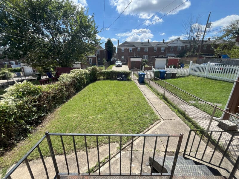 Rear yard with grass, alley access, and parking pad.
