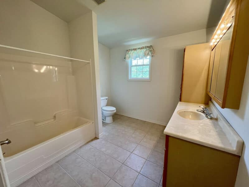 Full bathroom with tub/shower, tiled flooring, and vanity.