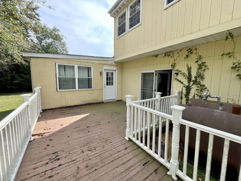 Rear deck with white railing attached to home.