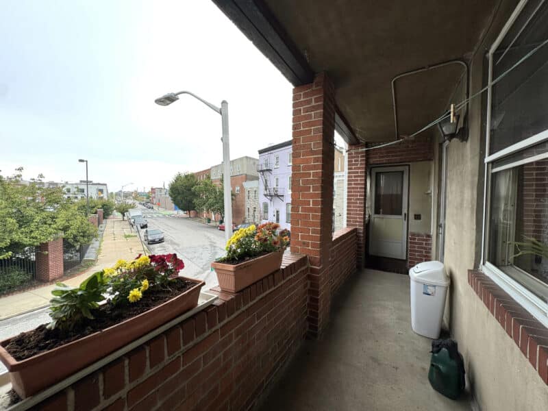 Alternate view of balcony with flower boxes and planters along the brick wall.