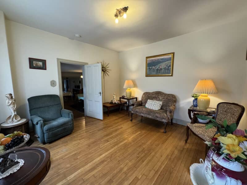 Sitting room with hardwood floors, loveseat, chairs, and decorative tables.