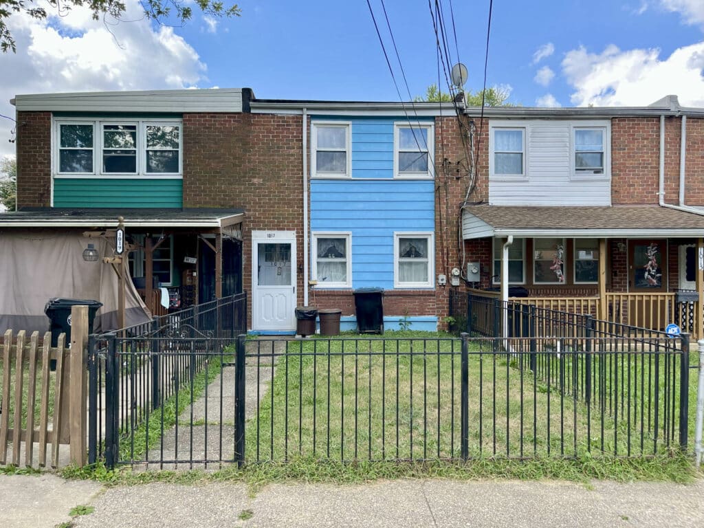 Front exterior of two-story brick townhome at 1017 Fredonia Court in the Riverview subdivision of Halethorpe, Baltimore County, with fenced front yard.