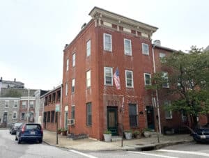 Exterior view of 1021 Stiles Street, a three-story red brick end-of-group building with American flag