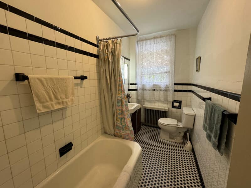 Bathroom with vintage black-and-white tile, bathtub, pedestal sink, and toilet.