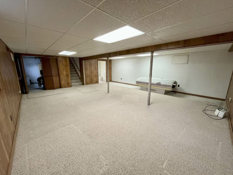 Finished basement rec room with carpeting and panel walls at 7245 Meadow Lane.