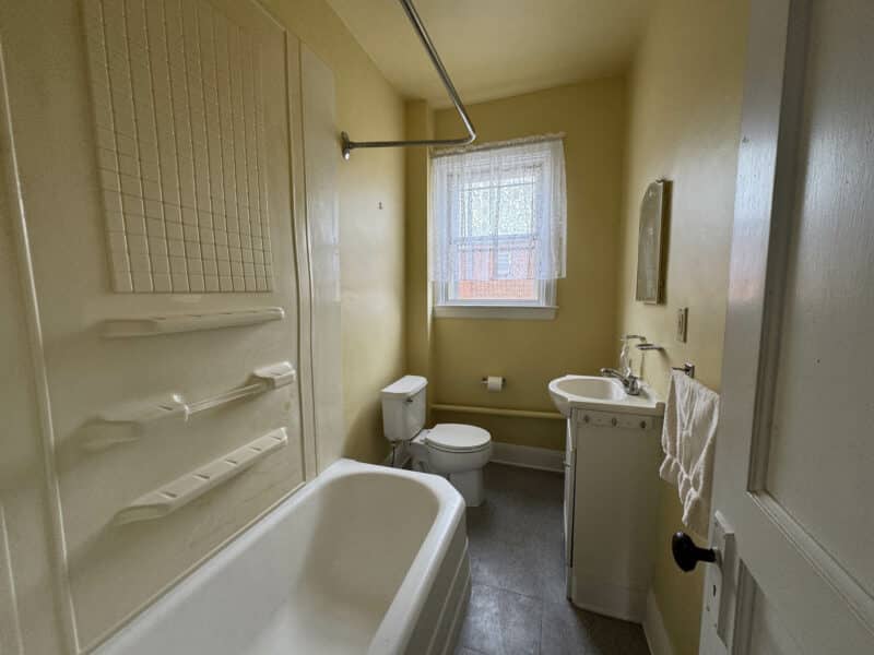 Yellow bathroom with tub, sink, and toilet.