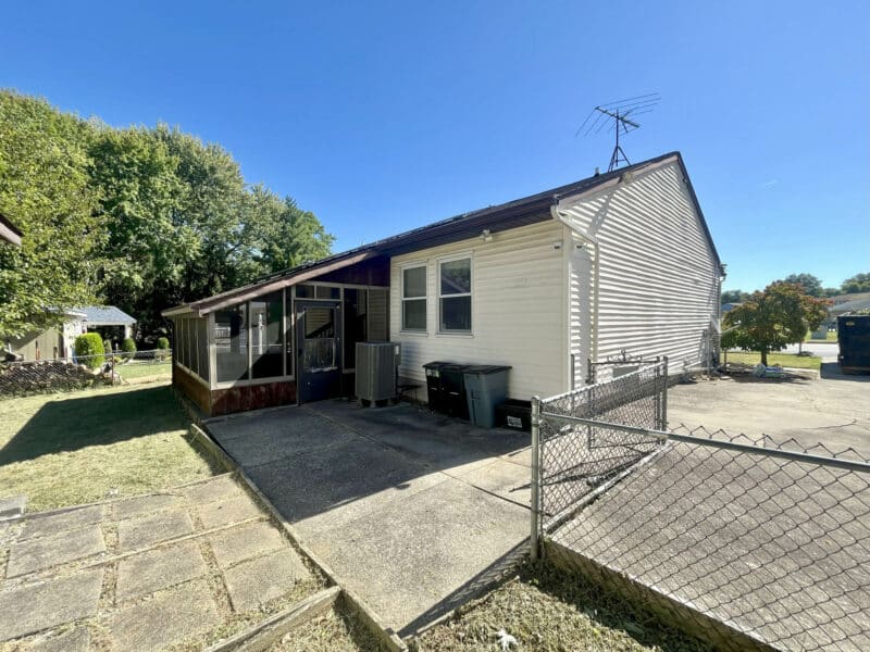 Rear exterior of rancher with screened porch, fenced yard, and paved patio area.