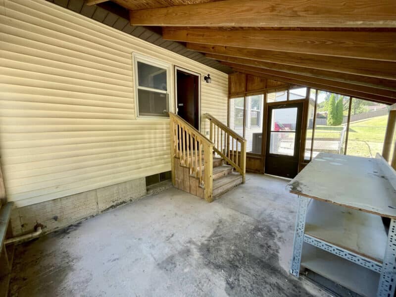 Covered screened porch area with concrete flooring and side entry steps.