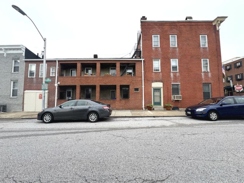 Street view of full brick property with covered porches.