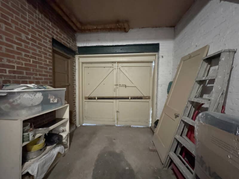Garage with shelving, ladder, and double entry doors.