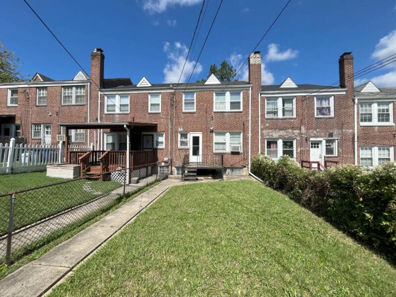 Rear view of Hillen townhome with fenced yard, alley access, and parking pad.