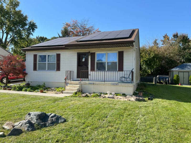 Front exterior of single-story rancher at 334 Royer Road in Westminster, MD, featuring vinyl siding, covered entry porch, landscaped yard, and solar panels on the roof.