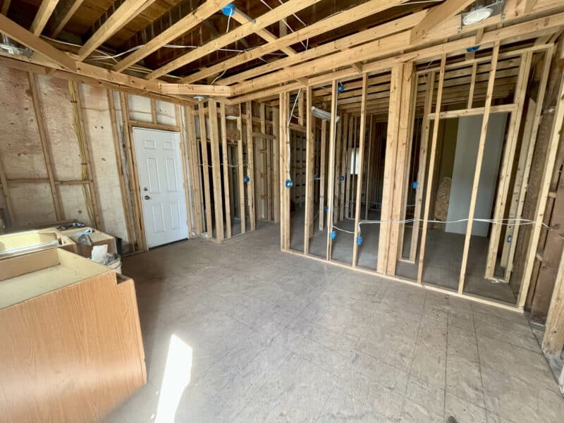 Framed entry area with open stud walls, door, and exposed ceiling joists.