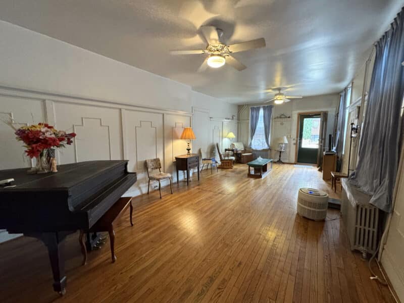 Long living room with hardwood floors, ceiling fans, and period-style furnishings