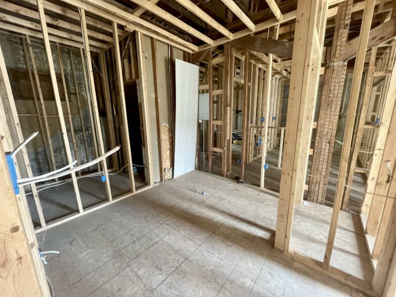 Open framed interior room with visible electrical rough-ins and large window.