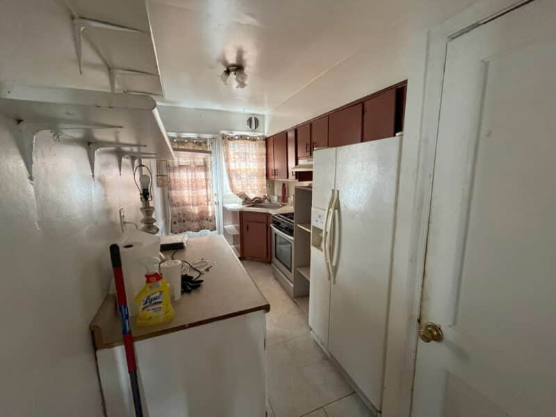 Kitchen with white appliances, wood cabinets, and vinyl tile flooring.
