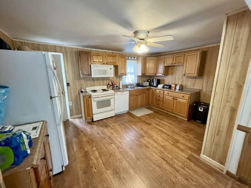 Spacious kitchen with cabinets, white appliances, and ceiling fan
