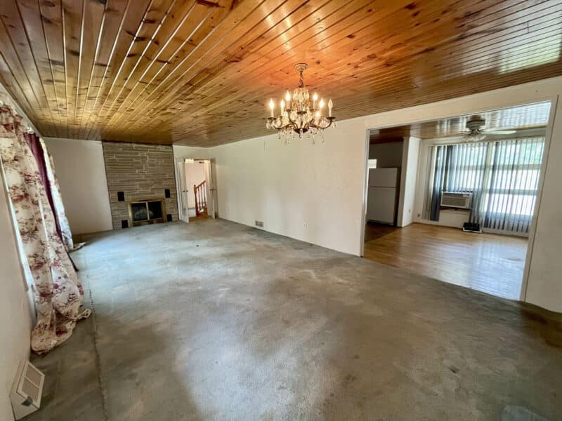 Open living and dining area with chandelier and wood ceiling.
