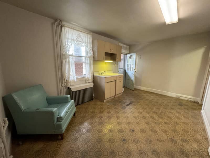 Upper-level room with vintage patterned carpet, small kitchenette, and lounge chair