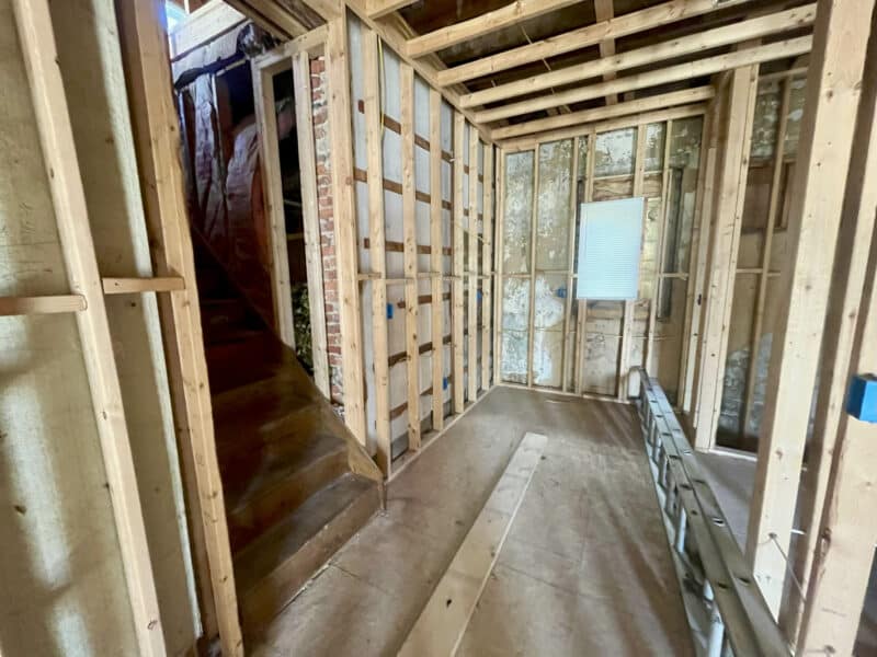 Stairwell area under construction with new wall framing and exposed brick.