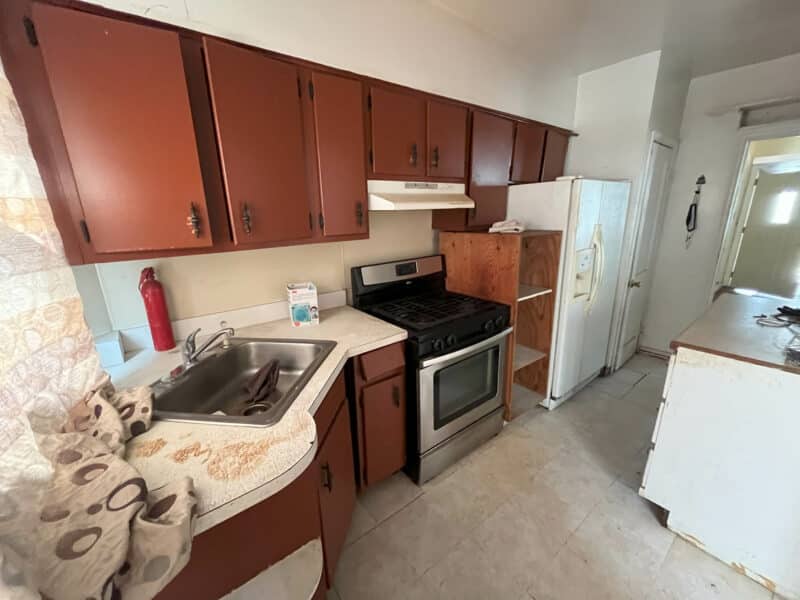 Second angle of kitchen showing wood cabinets, stainless gas range, and refrigerator.