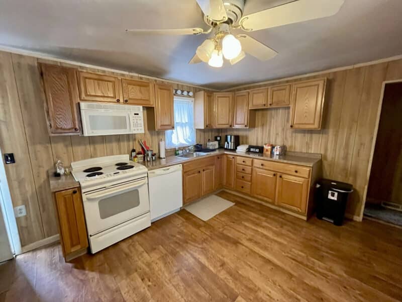 Kitchen alternate angle with stove, refrigerator, and wood-paneled walls