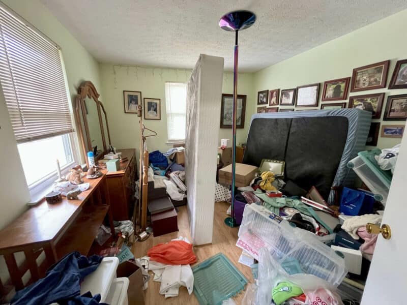 Cluttered bedroom at 2009 Halethorpe Avenue in Halethorpe Terrace, Baltimore County, with hardwood floors, windows, and space for furnishings, requiring renovation.