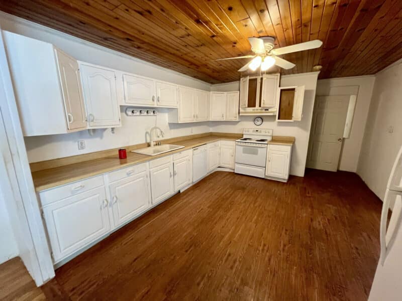 Kitchen with white cabinets, wood-look flooring, and paneled ceiling.