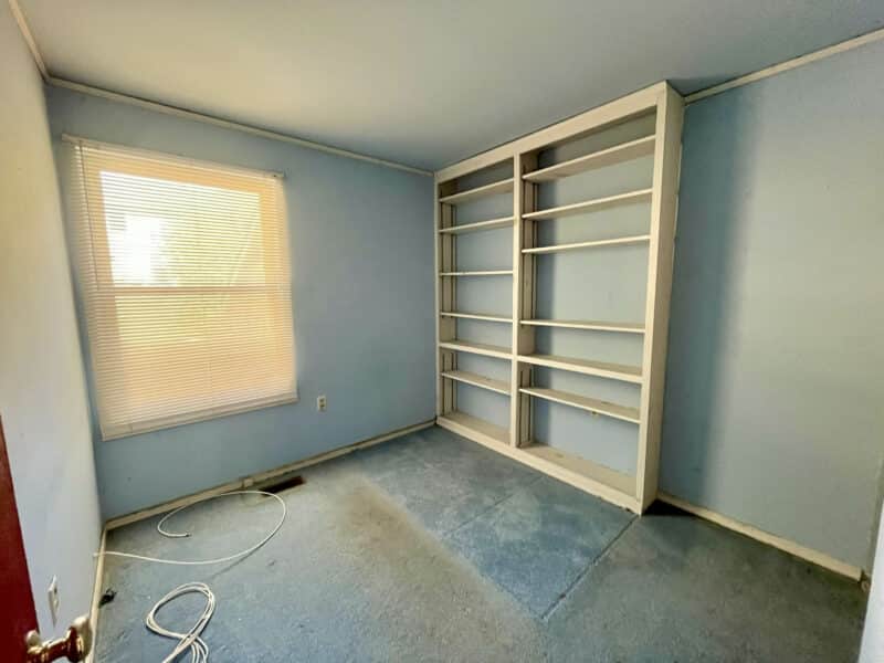 Bedroom with built-in shelving unit and blue-painted walls.