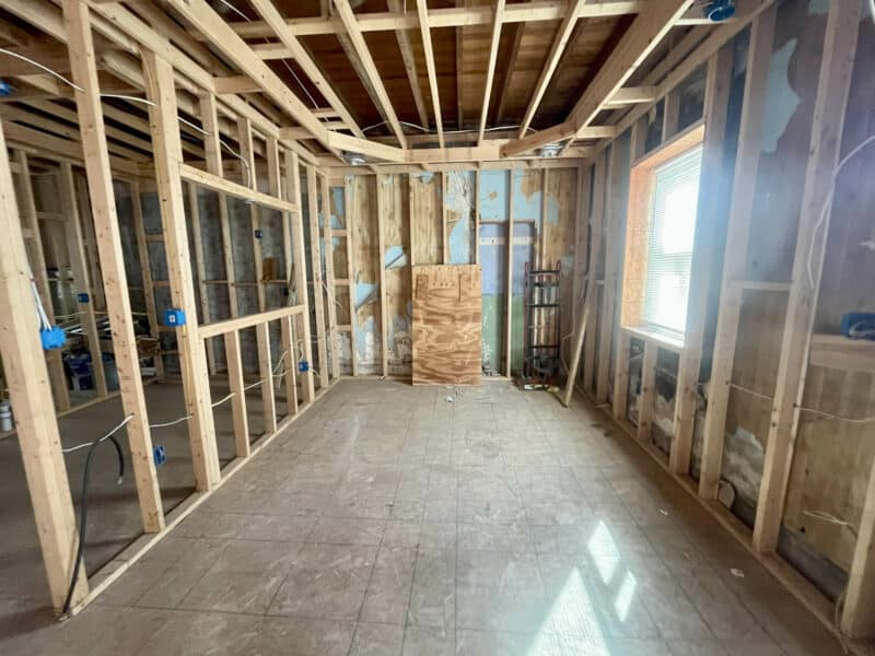 Wide view of open framed room with subfloor and exposed ceiling joists.